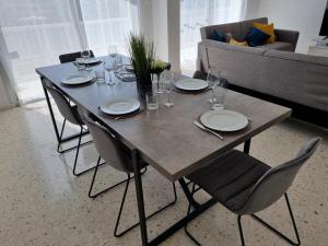 a table with chairs and plates and glasses on it at Diamond Sea View Penthouse in Paphos City