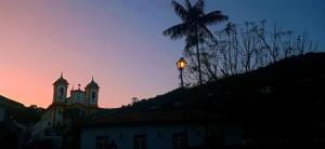 a street light in front of a building with a sunset at Nuh Hostel in Ouro Preto