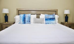 キングストンにあるComfort Homes Jamaicaの白い大型ベッド(青い枕、ランプ2つ付)
