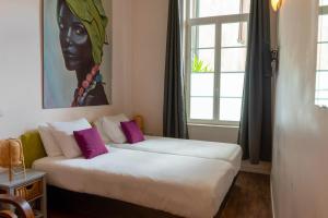 two beds in a room with a painting on the wall at Hôtel Croix Baragnon in Toulouse