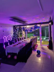 une grande salle à manger avec une grande table et un éclairage violet dans l'établissement Vila ČAROLIJA Futog, à Futog