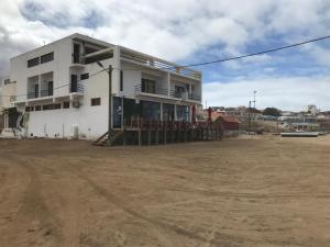 un edificio bianco con un campo di terra davanti di Beach Rotxa a Vila do Maio