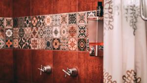 a bathroom with a tiled wall with a shower curtain at Hotel Casa Guivá in Oaxaca City +48 photos