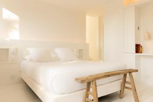 a white bedroom with a white bed and a wooden bench at Ô PLUM'ART Chambres de caractère in Giverny