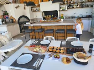 a woman standing in a kitchen with a table with food at Made of Blue luxury suites collection in Rethymno