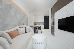 un soggiorno con divano bianco e TV di Baltini Premium Apartament Baltic Marina Residence a Kołobrzeg