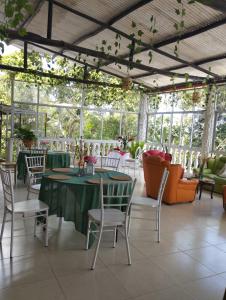 a conservatory with a table and chairs and windows at La Cabaña Eco Hotel in Suaita