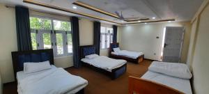 Cette chambre comprend 3 lits et une fenêtre. dans l'établissement Alpen Hotel Skardu, à Skardu