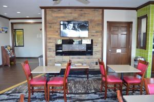 Quality Inn Coralville - Iowa River Landing في كورالفيل: غرفة انتظار مع طاولات وكراسي وتلفزيون