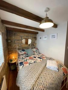 um quarto com uma cama e uma parede de pedra em Cosy 400 yr old Cottage, Flowergate, Whitby em Whitby