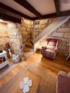 uma sala de estar com uma cadeira e uma parede de pedra em Cosy 400 yr old Cottage, Flowergate, Whitby em Whitby