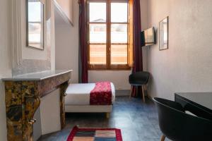 トゥールーズにあるHôtel Croix Baragnonのベッドと窓が備わる小さな客室です。