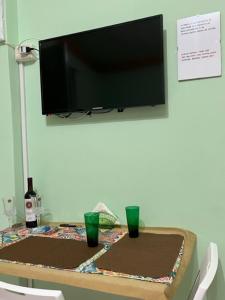 uma mesa com duas chávenas verdes e uma televisão na parede em Holiday Gole Alcantara Graniti Room em Graniti