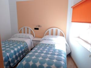 2 Betten in einem kleinen Zimmer mit Fenster in der Unterkunft Casa Rural Estajero in Muñana