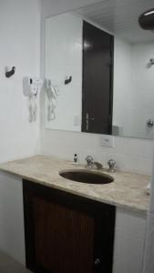 a bathroom counter with a sink and a mirror at Essência Hotel Francisco Beltrão in Francisco Beltrão