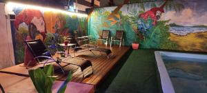 Cette chambre comprend une piscine avec des chaises et une fresque murale. dans l'établissement Oceanic Hostel, à Balneário Camboriú