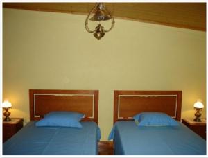 two beds in a bedroom with blue sheets and a lamp at Casa do Planalto Mirandês in Miranda do Douro