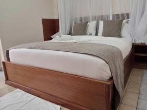 a large bed with a wooden frame in a bedroom at Logmma Regency Hotel in Kakamega