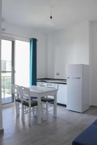 a white kitchen with a table and a refrigerator at LUMNIK - Hotel & Apartments in Lezhë