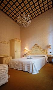 a bedroom with a large white bed with a chandelier at Hotel Torino in Venice