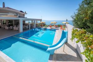 a swimming pool with a slide in front of a house at Hotel Dimitra in Ligia