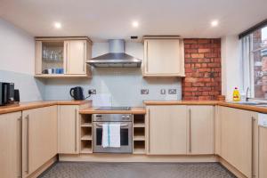 a kitchen with wooden cabinets and a brick wall at Lovely flat in central Manchester in Manchester