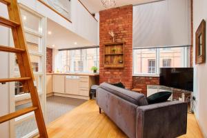 a living room with a couch and a brick wall at Lovely flat in central Manchester in Manchester