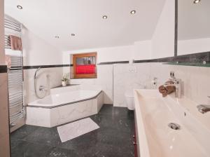 a white bathroom with a tub and a toilet at Landhaus Sabrina in Mayrhofen