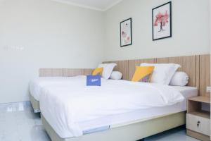 1 dormitorio con 2 camas con sábanas blancas en Singgahsini Rungkut Syariah, en Medokanayu