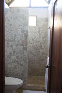a bathroom with a stone shower with a toilet at Rancho Capulin B&B in Tárcoles