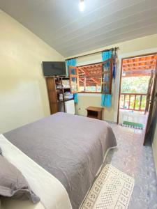 a bedroom with a bed and a tv and two windows at Pousada Nenzinha in Sao Jorge