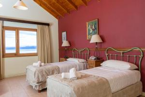 two beds in a room with red walls at Hotel Las Dunas in El Calafate