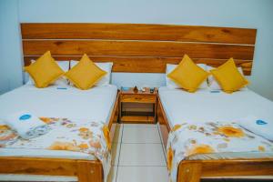 2 camas en una habitación pequeña con almohadas amarillas en Hotel Cielo Tarapoto, en Tarapoto