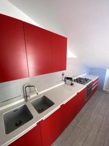 Una cocina con gabinetes rojos y un fregadero. en CASA CARAGOL ALGHERO, en Alghero