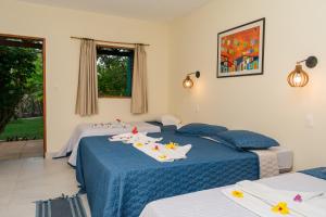 a bedroom with two beds with blue sheets and flowers on them at Pousada Lagoa Mar in São Miguel do Gostoso