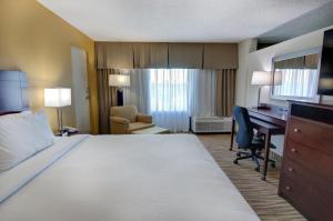 a hotel room with a large bed and a desk at Holiday Inn St. Petersburg N - Clearwater by IHG in Clearwater
