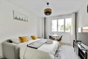 a white bedroom with a bed and a table at Chic studio near Paris - La Defense in Bezons