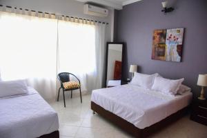 a bedroom with two beds and a chair and a mirror at VG Villa Gloria in Santa Marta
