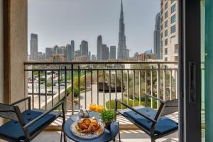 een balkon met 2 stoelen en een tafel met een bord eten bij Durrani Homes - Modern Living at Burj Views in Dubai