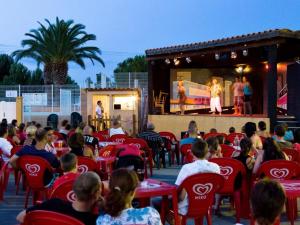 Tropical Bungalow 2 في فيك- لا-غارديول: حشد من الناس يجلسون على كراسي حمراء يشاهدون المسرح