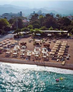 eine Gruppe von Stühlen und Tischen an einem Strand neben dem Wasser in der Unterkunft premium park apart otel in Kemer