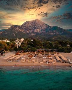 a beach with lounge chairs and a mountain in the background at premium park apart otel in Kemer