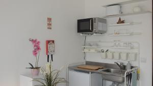 a kitchen with a sink and a microwave at Hospedaria Do Senhor da Pedra in Óbidos