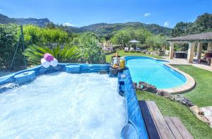 a large swimming pool in a yard next to a house at Owl Booking Villa Can Demana - Retreat in the Midst of Nature in Pollença