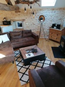 uma sala de estar com mobiliário de couro e uma parede de tijolos em Gite Pays de Joie 
