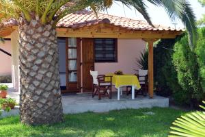a table and chairs under a pergola next to a palm tree at Haus Katerina in Vourvourou