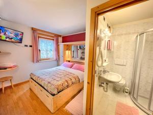 um quarto com uma cama, um lavatório e um chuveiro em Garni Francescato em Livigno