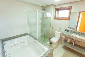 a bathroom with a tub and a toilet and a shower at Hotel Imperium Village in Sarapuí