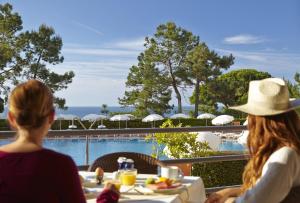 two women sitting at a table looking out at a pool at PortoBay Falesia in Albufeira