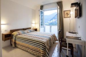 a bedroom with a bed and a desk and a window at La Casa di Carla in Ravello